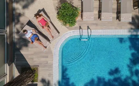 Due donne rilassate a bordo della piscina di Milano Marittima, con lettini e ombrelloni.