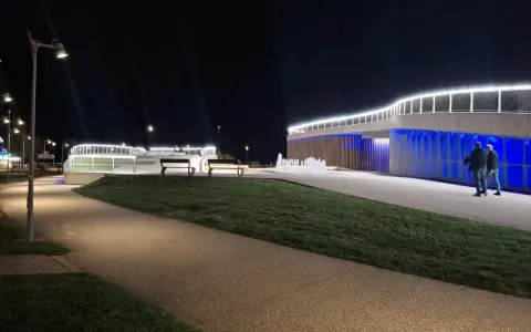 Passeggiata serale a **Piazzale Kennedy Rimini**, con fontane luminose e architettura moderna illuminata.