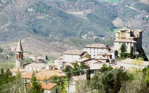 Borgo medievale con torre campanaria e rocca imponente, immerso tra le colline verdi. Un angolo di storia vicino a Marecchia Rimini.