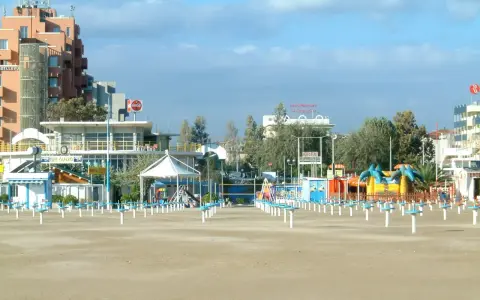 Spiaggia di Rimini a settembre, con ombrelloni chiusi e giochi per bambini in attesa della prossima stagione.