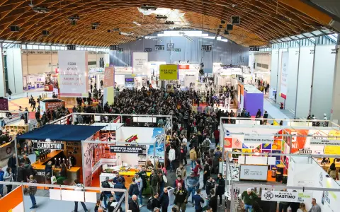 Folla in un padiglione fieristico, un'attrazione beer&food con stand e degustazioni.