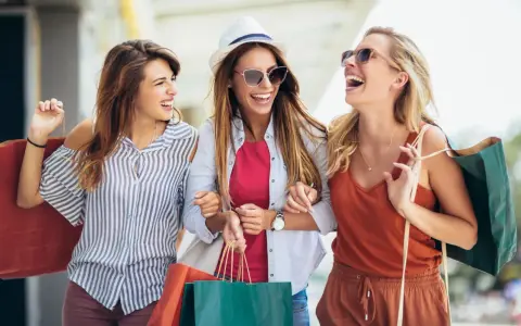 Tre amiche ridono felici con borse della spesa, dopo un pomeriggio di shopping nel cesenatico centro negozi.