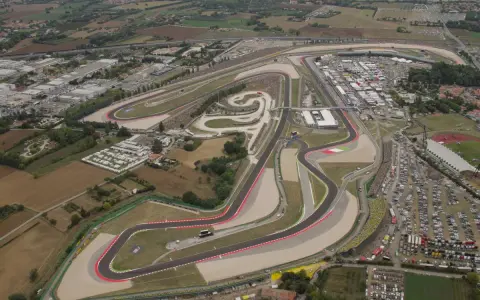 Vista aerea del circuito di Misano, noto anche come circuito San Marino, con tribune piene di spettatori e un vasto parcheggio.