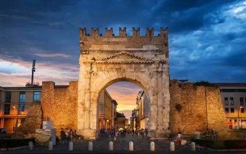 Arco d'Augusto a Rimini al tramonto, con il suo skyline suggestivo e le nuvole drammatiche.