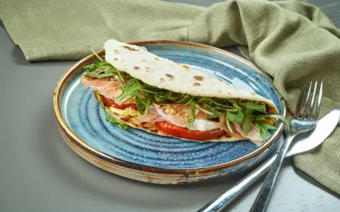 Piadina romagnola con prosciutto, mozzarella, pomodoro e rucola, un classico del rimini food.