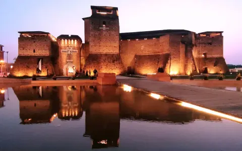 Castello Sismondo illuminato di sera, con riflessi sull'acqua. Un luogo che evoca la magia del cinema, come un museo felliniano a Rimini.