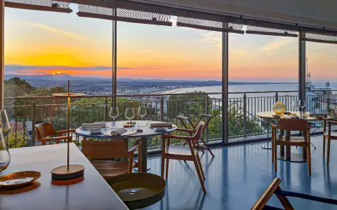 Tavoli apparecchiati in un ristorante con vista sul tramonto sul mare. Un'atmosfera magica per i ristoranti a Gabicce Monte.