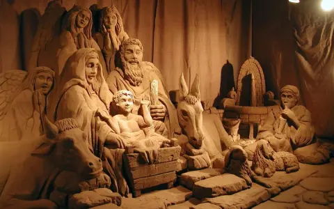 Un suggestivo presepe di sabbia a Rimini, con figure scolpite nella sabbia, tra cui angeli, la Sacra Famiglia, animali e un pastore.