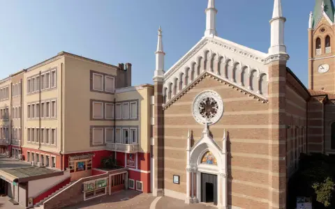 Facciata di una chiesa a Rimini con campanile e edificio adiacente.