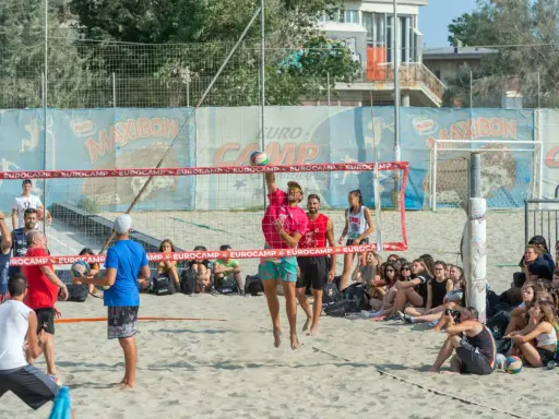 Partita di camp volley Cesenatico: un giocatore salta per colpire la palla mentre gli spettatori osservano.