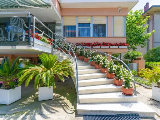L'ingresso fiorito del hotel dell'amarissimo, con scale bianche ornate da piante e fiori, invita ad entrare.