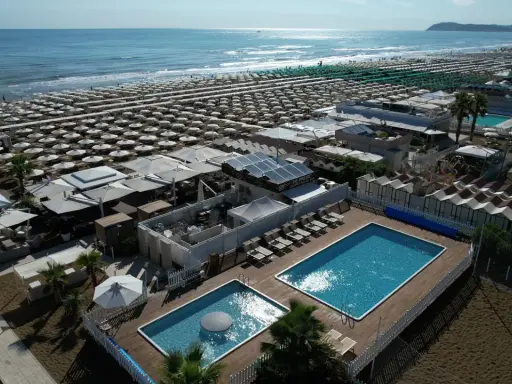 Vista aerea della spiaggia Le Palme Riccione con ombrelloni, piscine e cabine.