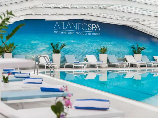 Rilassati nei bagni Riccione con piscina, un'oasi di benessere con lettini e teli blu.