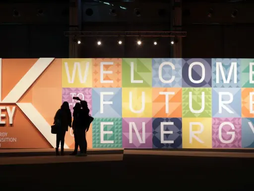 Persone silhouette davanti a un grande pannello colorato con la scritta "WELCOME TO FUTURE ENERGY" alla fiera Rimini Key Energy.