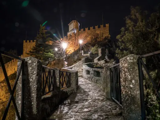 Sentiero lastricato di notte, illuminato da lampioni, conduce verso il castello di San Marino, il passo delle streghe.