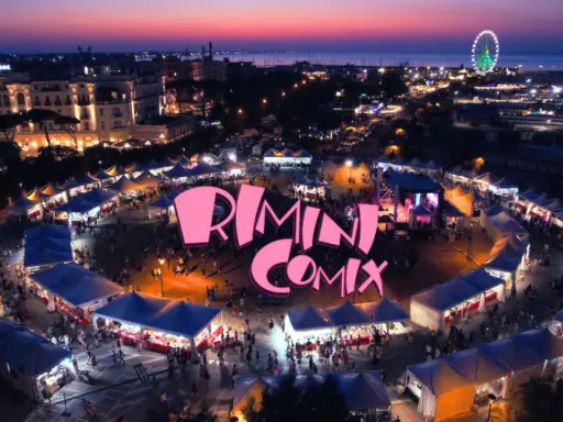 Un vivace evento serale a Rimini Comix, con bancarelle illuminate, una ruota panoramica e il logo rosa che domina la scena.