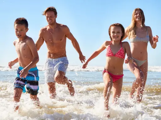 Famiglia corre felice nel mare del lido di Savio, spruzzi d'acqua e sole.