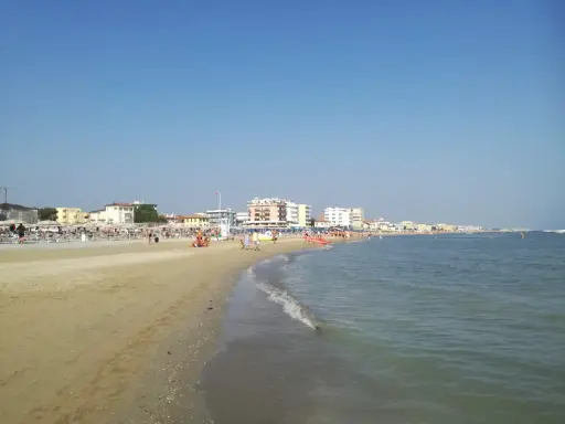 Spiaggia affollata a Viserbella mare, con ombrelloni, lettini e persone che si godono il sole e il mare azzurro sotto un cielo limpido.