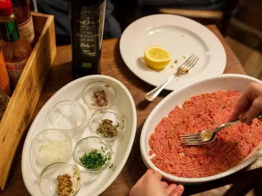 Preparazione di tartare di carne in un ristorante a Rimini, con condimenti e olio EVO.