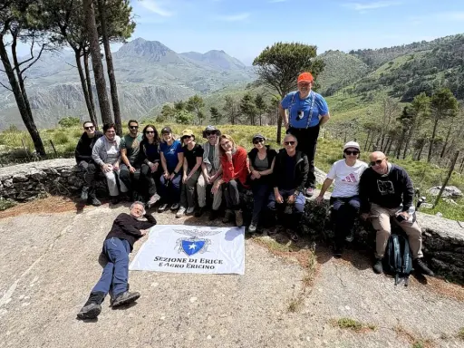 Gruppo di escursionisti con bandiera della Sezione di Erice e Agro Ericino, in cima al monte Gradara, con vista panoramica sulla valle.
