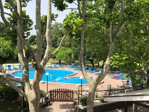 Piscina azzurra e lettini prendisole al **hotel Faro San Mauro Mare**, tra alberi rigogliosi.