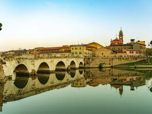Ponte di Tiberio a Rimini, un luogo che evoca la magia di Fellini, con le sue arcate che si specchiano nell'acqua calma.