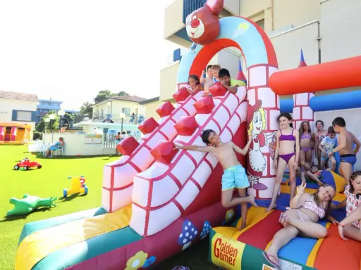 Bambini si divertono sulle giostre gonfiabili a Bellaria, scivolando e giocando in un parco acquatico pieno di allegria.