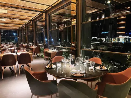 Interni eleganti del miglior ristorante di Rimini, con tavoli apparecchiati e vista notturna sulla città.