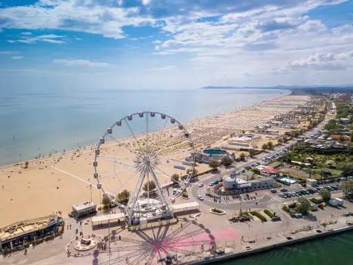 Vista aerea delle spiagge romagna con ruota panoramica, ombrelloni e mare azzurro.
