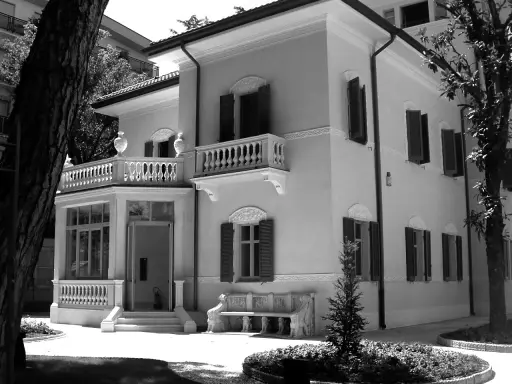 Villa Franceschi a Riccione, un'elegante dimora con balconi e un ingresso accogliente, circondata da alberi e un giardino curato.