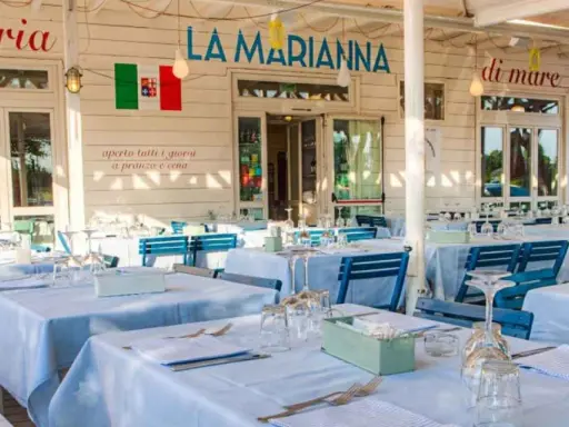 La Marianna Rimini, trattoria sul mare, con tavoli apparecchiati all'esterno sotto un grande albero.
