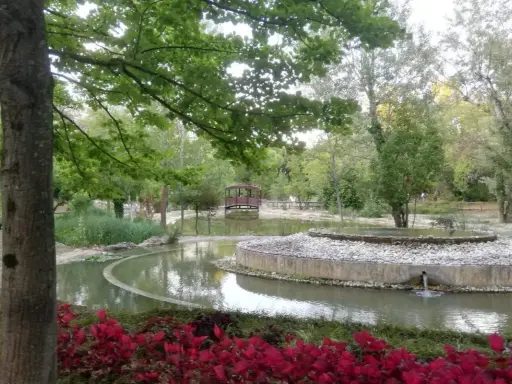 Un laghetto con un ponticello in legno e aiuole fiorite nel Parco della Resistenza a Riccione.