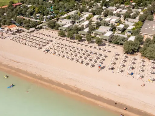Domenica di sole sulla spiaggia di Rivazzurra, con ombrelloni, lettini e bagnanti che si godono il mare.
