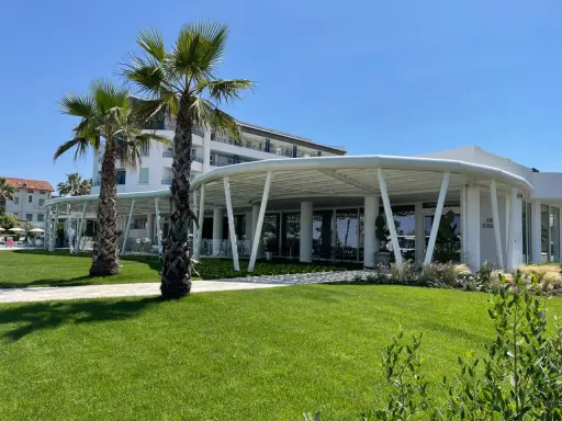 Palme e prato verde davanti a un moderno ristorante a Bellaria Igea, con un edificio bianco sullo sfondo.