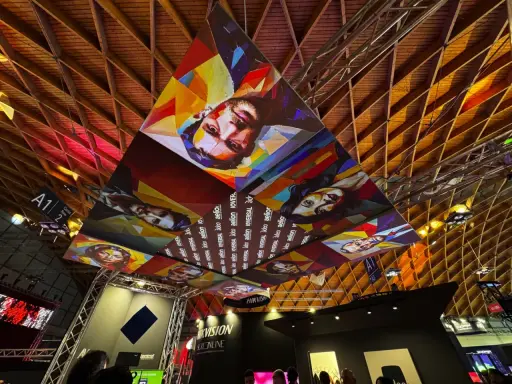 Installazioni artistiche colorate dominano il soffitto di una mir fiera, con volti stilizzati e il logo "Hikvision".