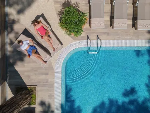 Due donne rilassate a bordo della piscina di Milano Marittima, con lettini e ombrelloni.