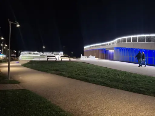 Passeggiata serale a **Piazzale Kennedy Rimini**, con fontane luminose e architettura moderna illuminata.