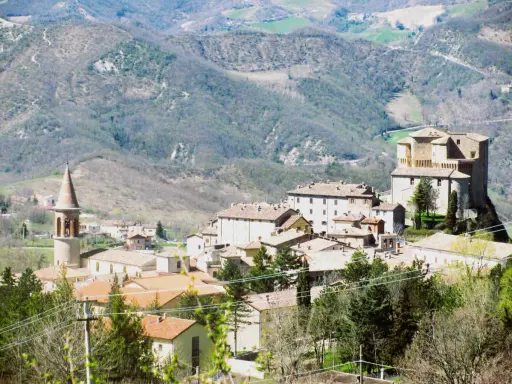 Borgo medievale con torre campanaria e rocca imponente, immerso tra le colline verdi. Un angolo di storia vicino a Marecchia Rimini.