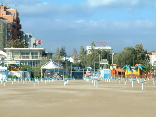 Spiaggia di Rimini a settembre, con ombrelloni chiusi e giochi per bambini in attesa della prossima stagione.