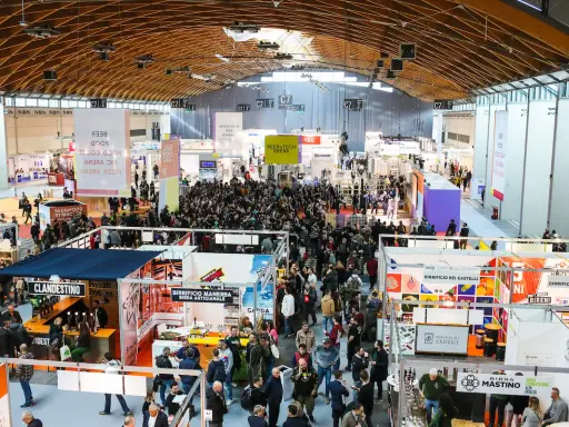Folla in un padiglione fieristico, un'attrazione beer&food con stand e degustazioni.