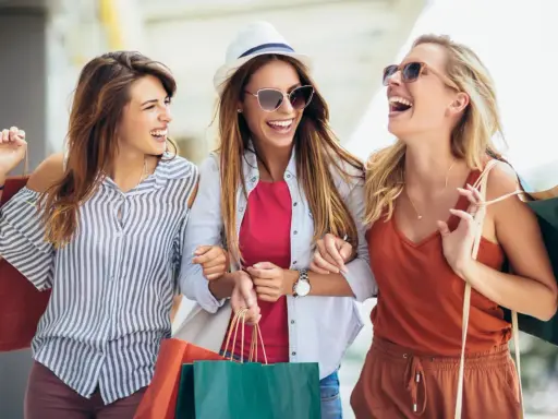 Tre amiche ridono felici con borse della spesa, dopo un pomeriggio di shopping nel cesenatico centro negozi.