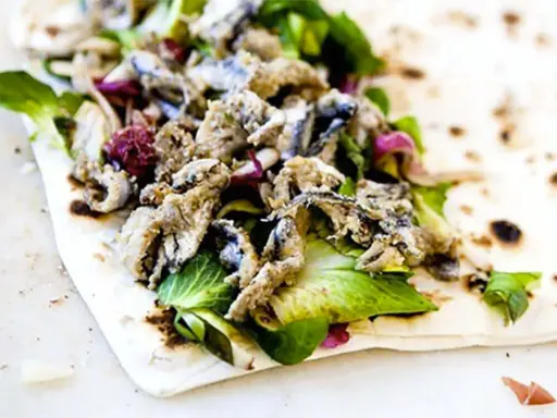 Sardoncini al testo su piadina con insalata fresca e cipolla rossa. Un sapore di mare e terra.