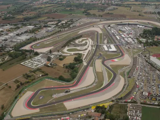 Vista aerea del circuito di Misano, noto anche come circuito San Marino, con tribune piene di spettatori e un vasto parcheggio.