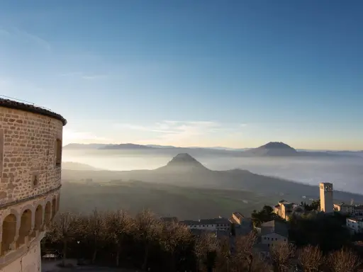 Panoramica di borghi vicino Riccione, con un antico torrione e colline nebbiose all'alba.