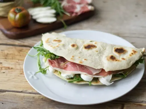 Piadina farcita con prosciutto crudo, mozzarella e rucola. Ecco come si farciscono le piadine per un pasto veloce e gustoso.