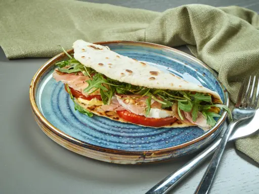 Piadina romagnola con prosciutto, mozzarella, pomodoro e rucola, un classico del rimini food.