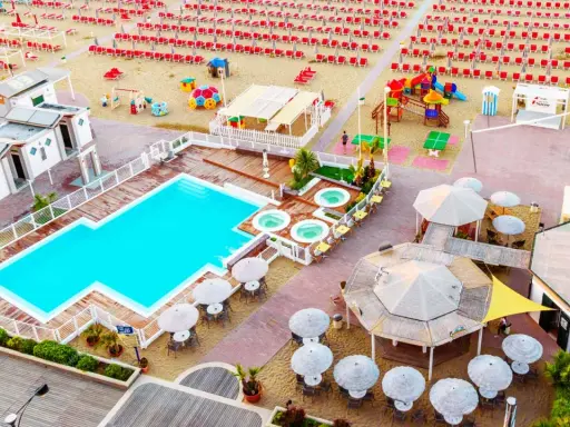 Vista aerea del lido delle sirene Cattolica: piscina, vasche idromassaggio, lettini rossi e ombrelloni sulla spiaggia.