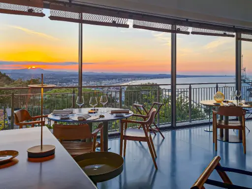 Tavoli apparecchiati in un ristorante con vista sul tramonto sul mare. Un'atmosfera magica per i ristoranti a Gabicce Monte.
