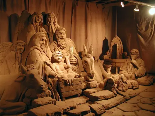 Un suggestivo presepe di sabbia a Rimini, con figure scolpite nella sabbia, tra cui angeli, la Sacra Famiglia, animali e un pastore.