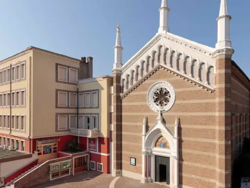 Facciata di una chiesa a Rimini con campanile e edificio adiacente.